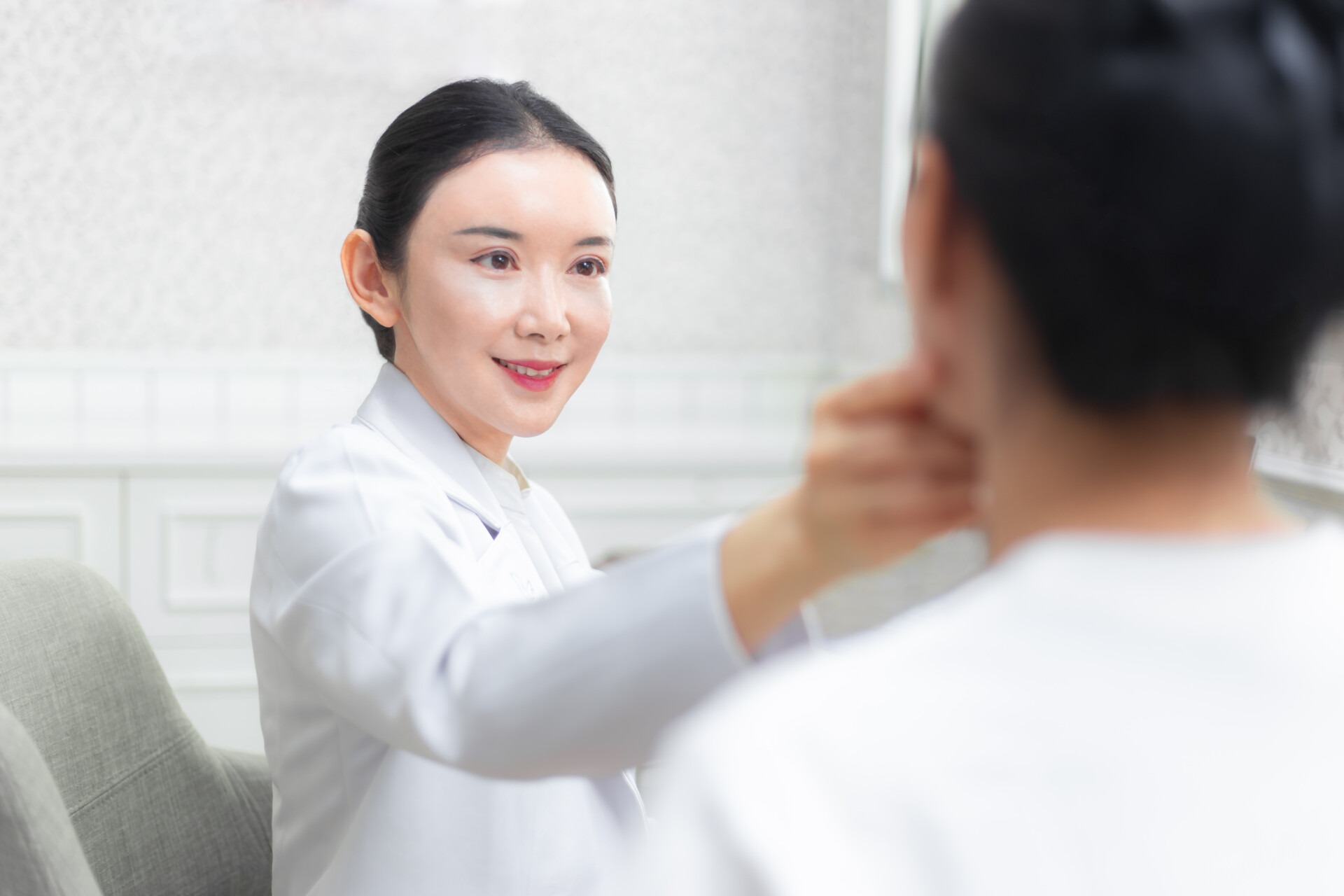 Young happy asian female doctor giving consulting session to her female patient in her office